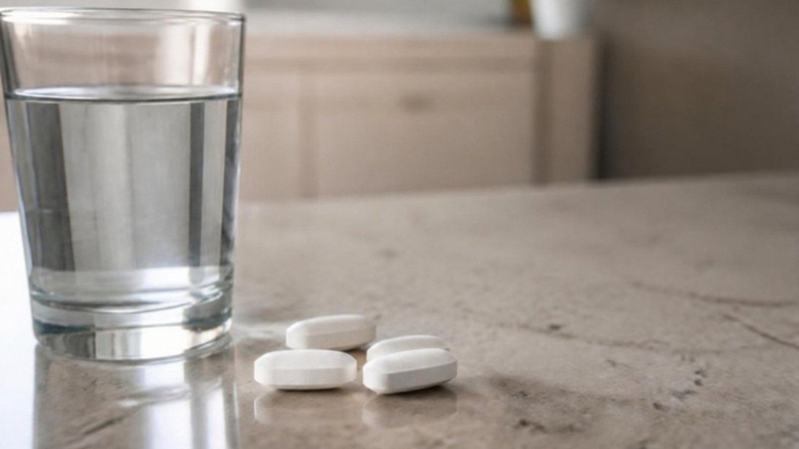 Calcium supplement tablets beside a glass of water on a kitchen counter, illustrating calcium supplements and weight loss