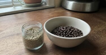Raw green coffee beans in a jar next to a bowl of roasted coffee beans, illustrating green coffee for weight loss