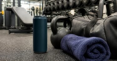 An energy drink can on a gym floor next to a kettlebell, gym bag and towel