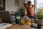 Guayusa tea: a pouch of guayusa tea with loose leaves, a glass teapot and mug of brewed tea on a home office desk in the morning