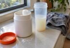 Waxy maize starch supplement powder in an open tub next to a shaker bottle on a kitchen counter